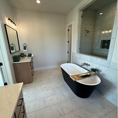 Primary bathroom with black freestanding tub and marble shower