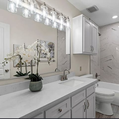 Bathroom vanity with quartz counter and glass sconce lighting