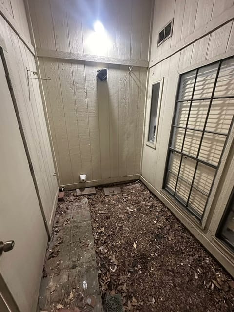 Sunroom before renovation, debris on the floor and bare paneling