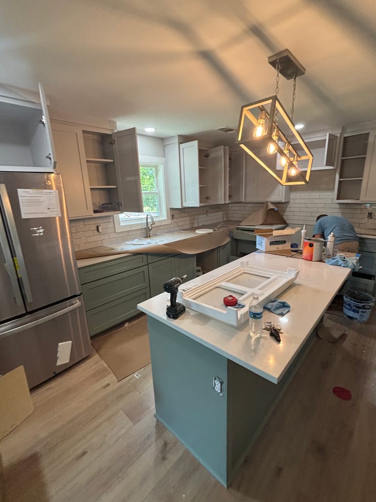 Custom kitchen island in sage green cabinetry with brass lantern pendants
