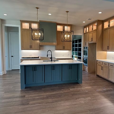 Kitchen island in deep teal with black fixtures and pendants