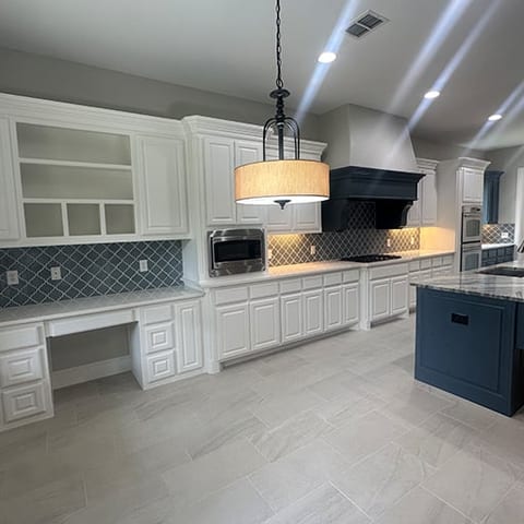 White kitchen with navy island and drum pendant lighting