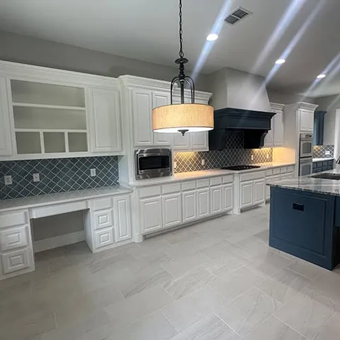 White kitchen with navy island and drum pendant lighting